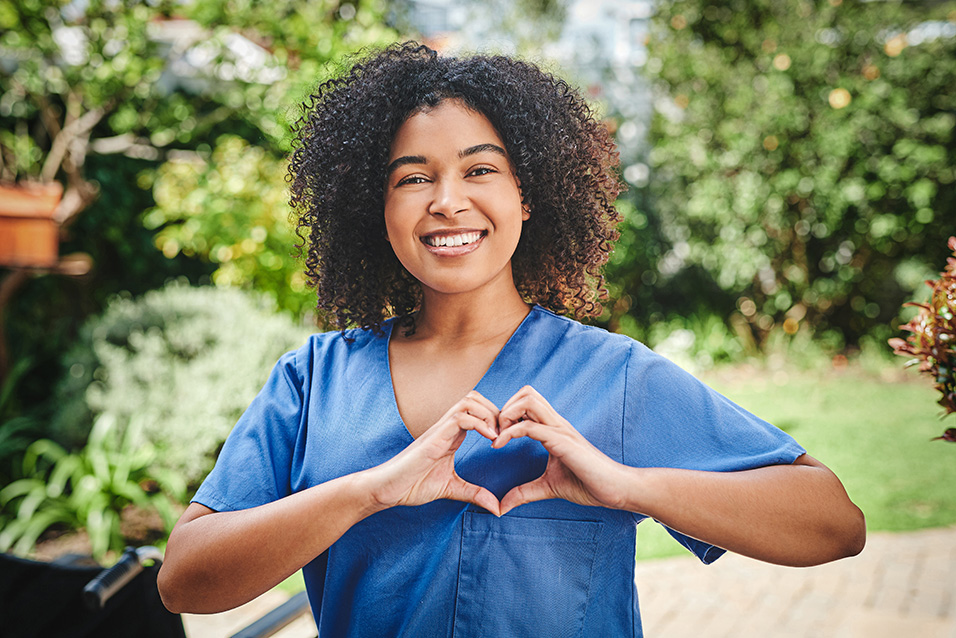 Smiling nurse making heart sign with hands
